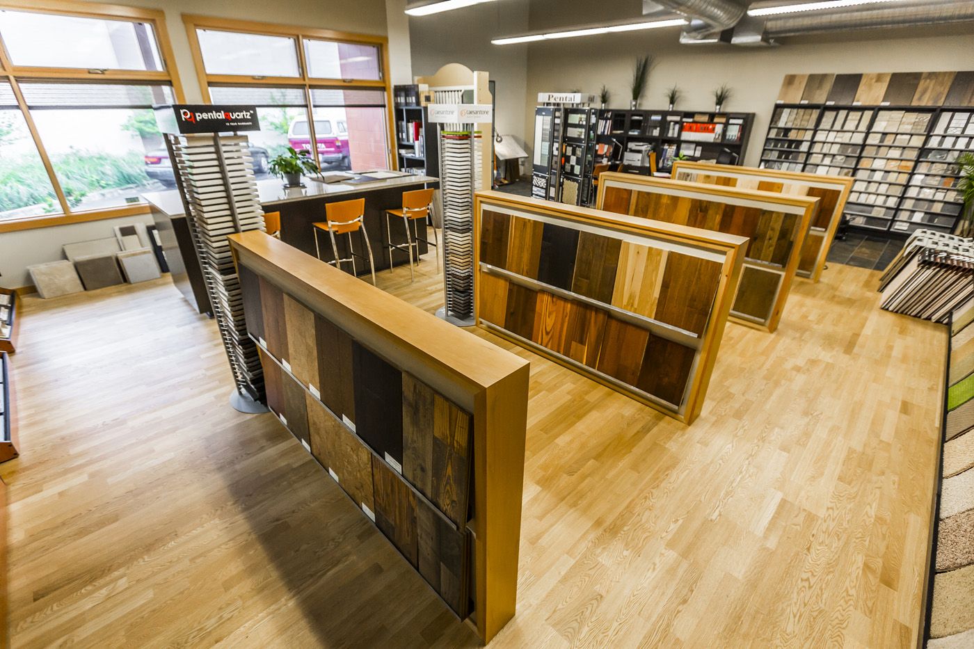Spacious flooring showroom with wall-mounted cabinetry, hardwood flooring samples, and staged furniture setups for home renovation inspiration.
