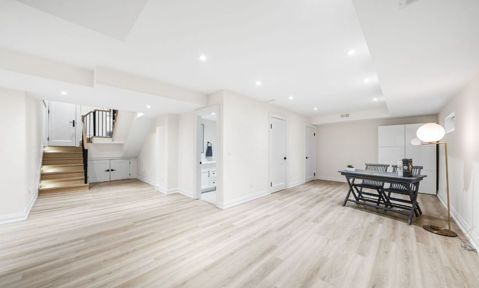 Finished basement with light neutral wall paint, vinyl flooring, and modern lighting in a Toronto renovation.